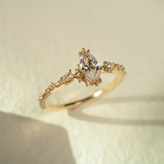 a yellow gold engagement ring with two pear shaped diamonds on the side, set against a plain white background