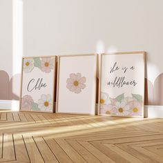 three framed art prints on the floor in front of a wall with pink and white flowers