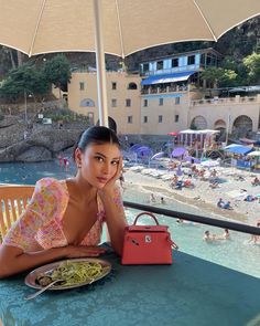 a woman sitting at a table with an umbrella over her head and food in front of her