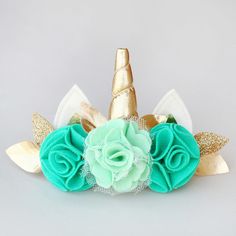 a green flower and gold leaf headband with a unicorn horn on it's side