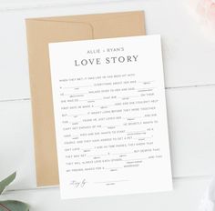 a love story card on top of a wooden table next to flowers and a plant