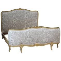 an antique style bed with gold trimmings and white fabric on the headboard