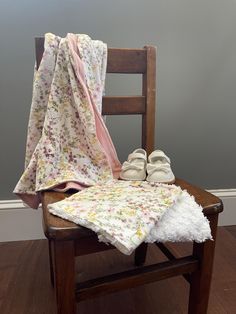 a pair of baby shoes sitting on top of a wooden chair next to a blanket