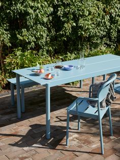 a blue table and two chairs on a brick patio