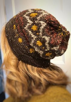 a close up of a person wearing a knitted hat with flowers on the side