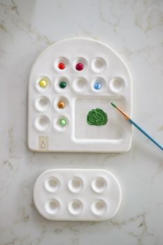 two white trays with different colored paints on them