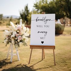 a sign that says, brollyn will you marry me? next to a bouquet of flowers