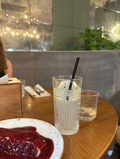 a woman sitting at a table with a plate of food and a drink in front of her