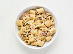 a white bowl filled with macaroni and cheese on top of a white table