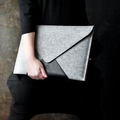 a woman is holding a gray felt envelope