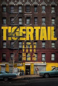 an advertisement for the movie tiger tail in front of a building with cars parked outside