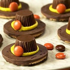 chocolate hats with candy candies on top of them sitting on a white platter