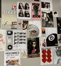 a refrigerator covered in posters and magnets next to a wall with pictures on it