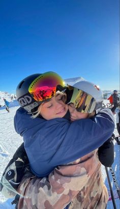 two people hugging each other in the snow on skis and holding their arms around one another