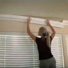 a woman standing in front of a window with blinds on the top of her head