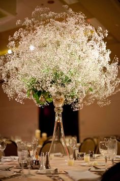 a vase filled with baby's breath flowers on top of a dining room table