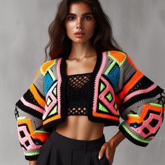 a woman wearing a colorful crochet jacket and black skirt with her hands on her hips