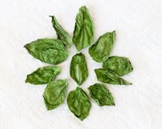 green leaves are arranged in the shape of a snowflake on a white surface