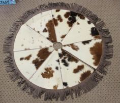 a brown and white cow print rug with fringes on it's center piece