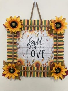 a wall hanging with sunflowers and the words fall in love written on it