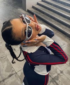 a woman with sunglasses on top of her head posing for a photo in front of some stairs