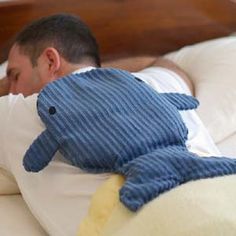 a man laying in bed with a stuffed animal on top of his back and sleeping next to him