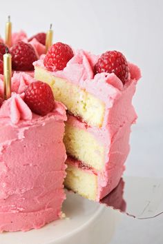 a cake with pink frosting and raspberries on top