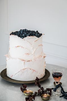 a white cake sitting on top of a table next to a glass of wine and figurines