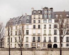 an old building with many windows and balconies on the top floor next to trees