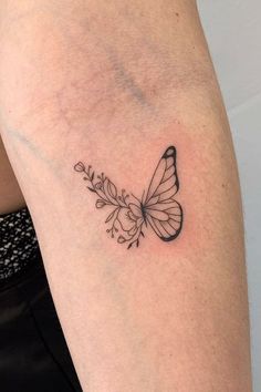 a black and white butterfly tattoo on the right arm, with small flowers around it