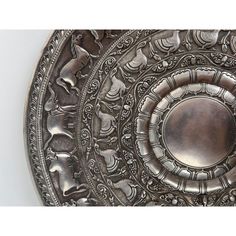 an ornate silver plate is shown on a white background, with the center part of it's design