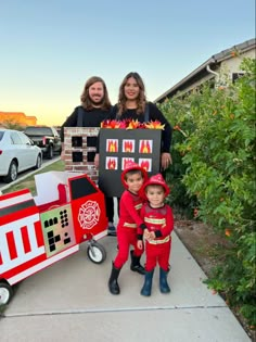 two women and one child are standing in front of a cardboard firetruck costume