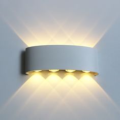 a white wall mounted light with three lights on it's side and one is turned on