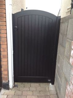 a black gate is open on the side of a brick building with a white door