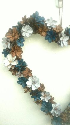 a heart shaped wreath with blue and white flowers hanging on a wall in the shape of a heart