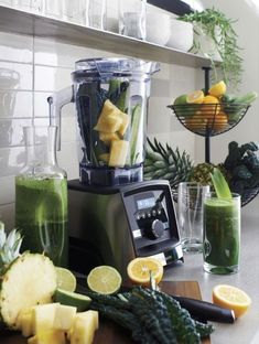 the blender is full of green smoothies and juices, along with pineapple slices