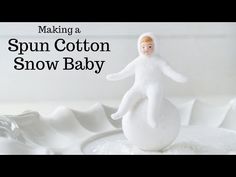 a white baby doll sitting on top of a snow ball