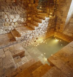 an indoor swimming pool with steps leading up to it and lit candles in the water