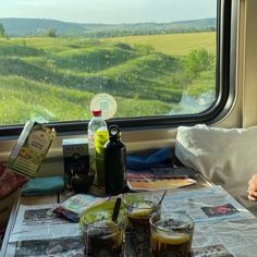 there is a table with drinks on it next to a window that looks out onto the countryside