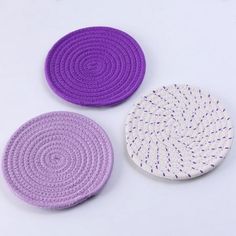 three crocheted coasters in different colors on a white surface with purple dots