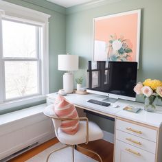 a desk with a computer on it and flowers in vases next to the window