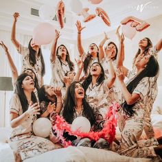 a group of women sitting on top of a bed with balloons and confetti