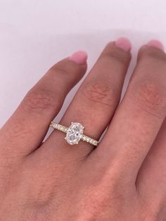 a woman's hand with a diamond ring on top of her finger and the other hand holding an engagement ring