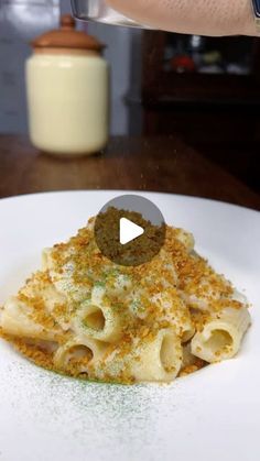 a person is sprinkling seasoning on some food in a white plate,