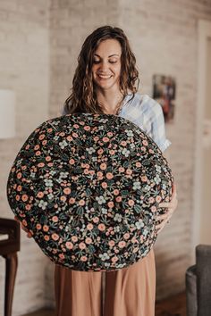 a woman holding a large round pillow in her hands