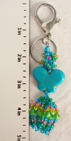 a pair of blue and green beads hanging from a metal keychain next to a ruler