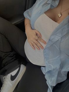 a woman sitting in the back seat of a car with her hand on her stomach