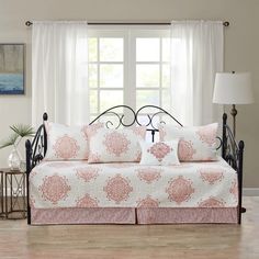 a day bed with pink and white pillows in front of a large window on a hard wood floor