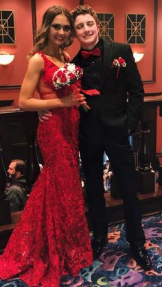 a man in a tuxedo standing next to a woman in a red dress