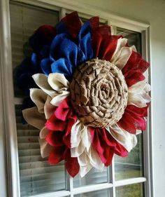 a patriotic wreath hanging on the front door with red, white and blue flowers in it